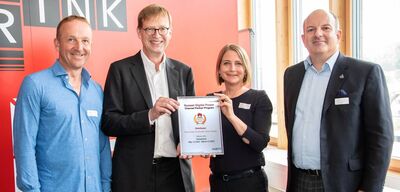 Une photo de quatre personnes dont deux présentant fièrement un contrat.