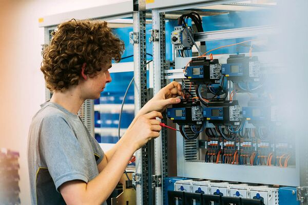 Un électricien réalise le câblage de contrôleurs pour l’automation du bâtiment