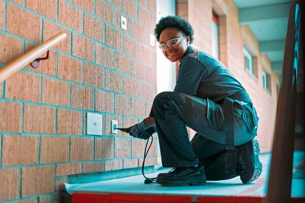 Une apprentie installatrice électricienne pose une prise de courant
