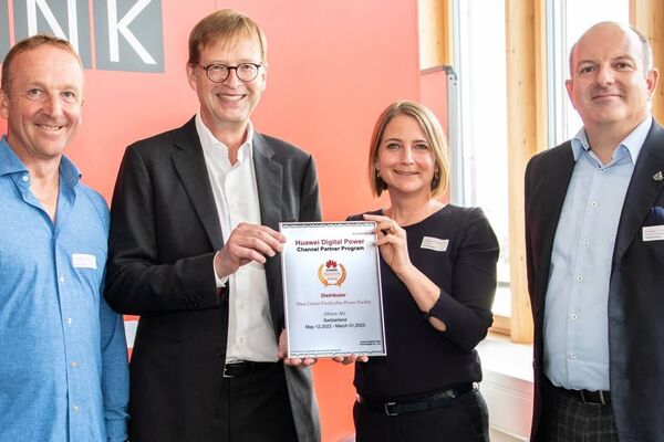 Une photo de quatre personnes dont deux présentant fièrement un contrat.